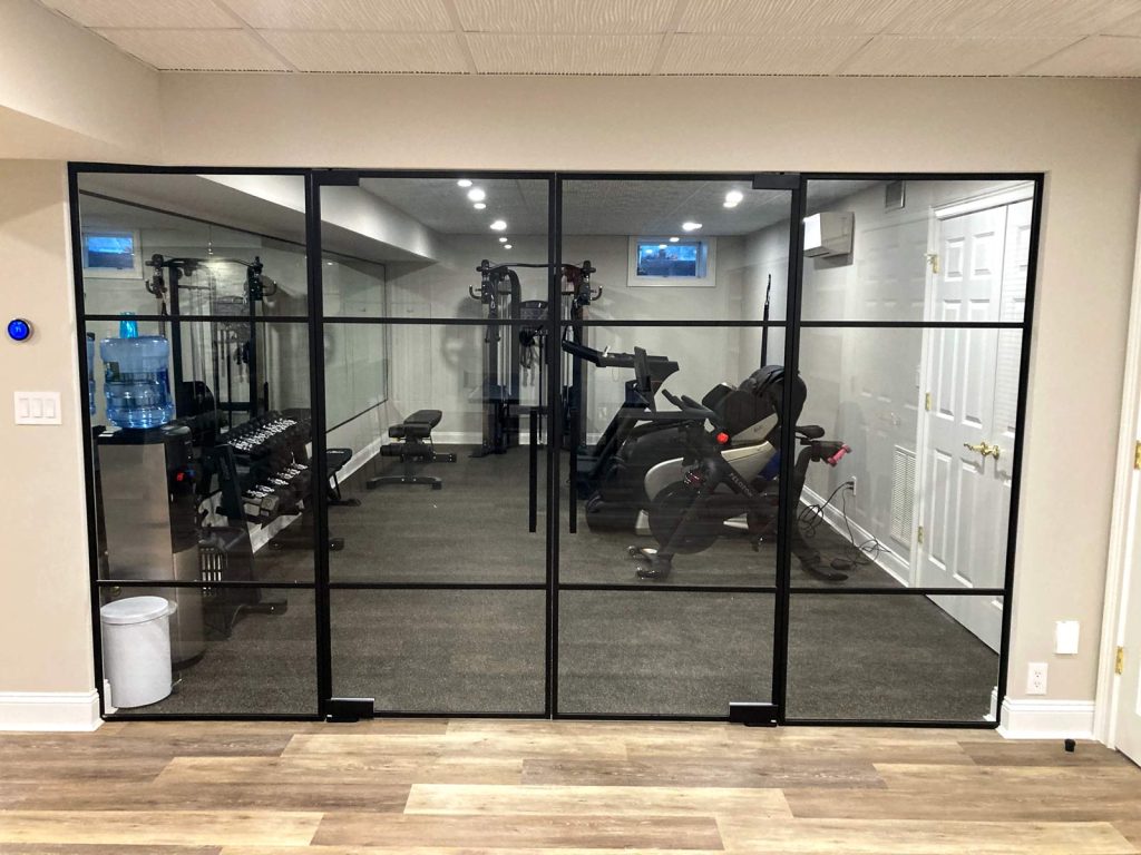 A recent basement renovation with a home gym and glass doors by White Maple Construction