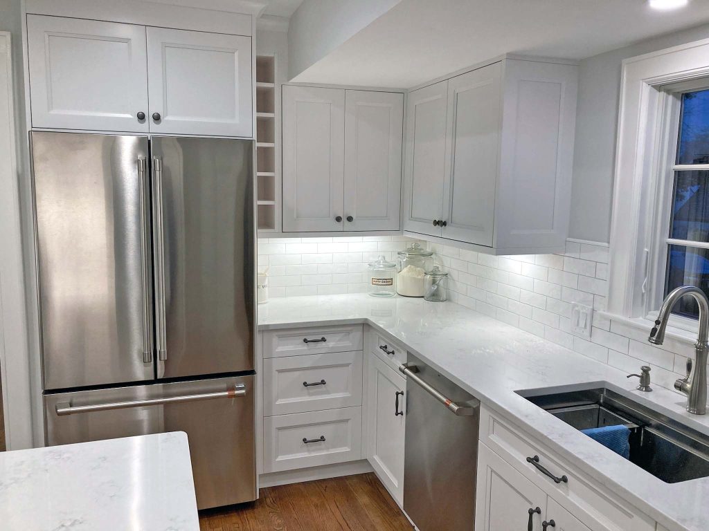 A modern white kitchen renovation with white marble countertops and white subway tiles by White Maple Construction