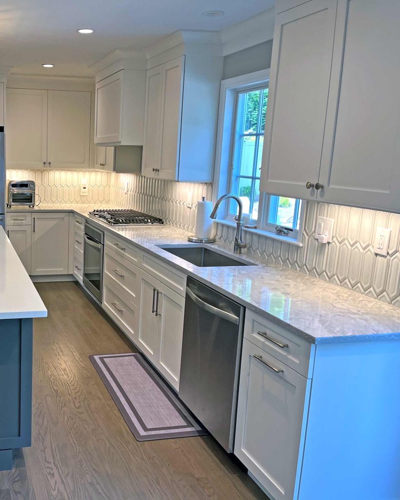 A modern kitchen remodel with white cabinets and wood floors by White Maple Construction