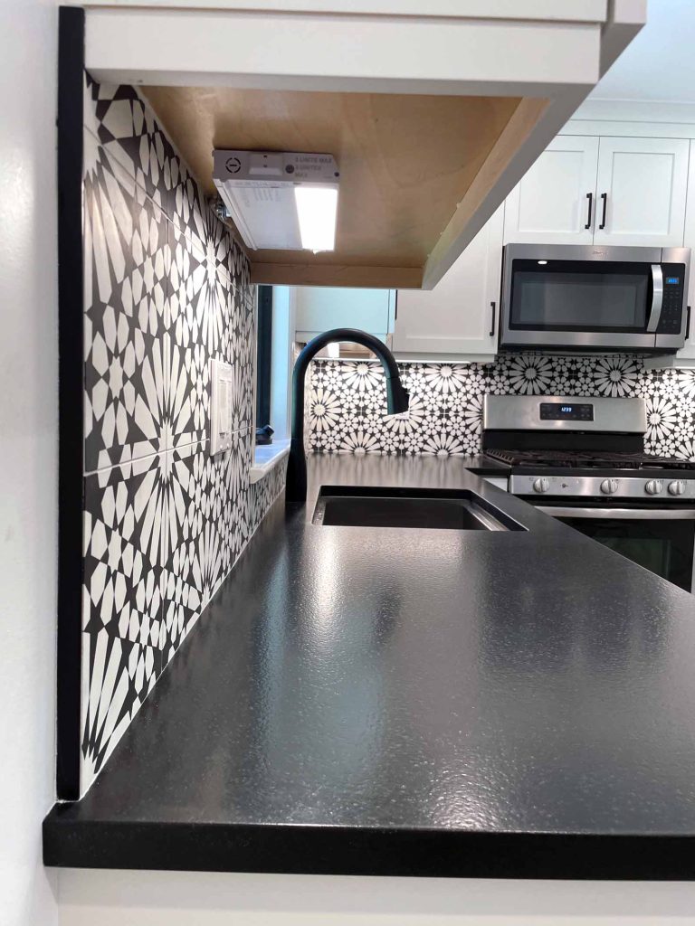 A kitchen remodel with ornate black and white backsplash by White Maple Construction