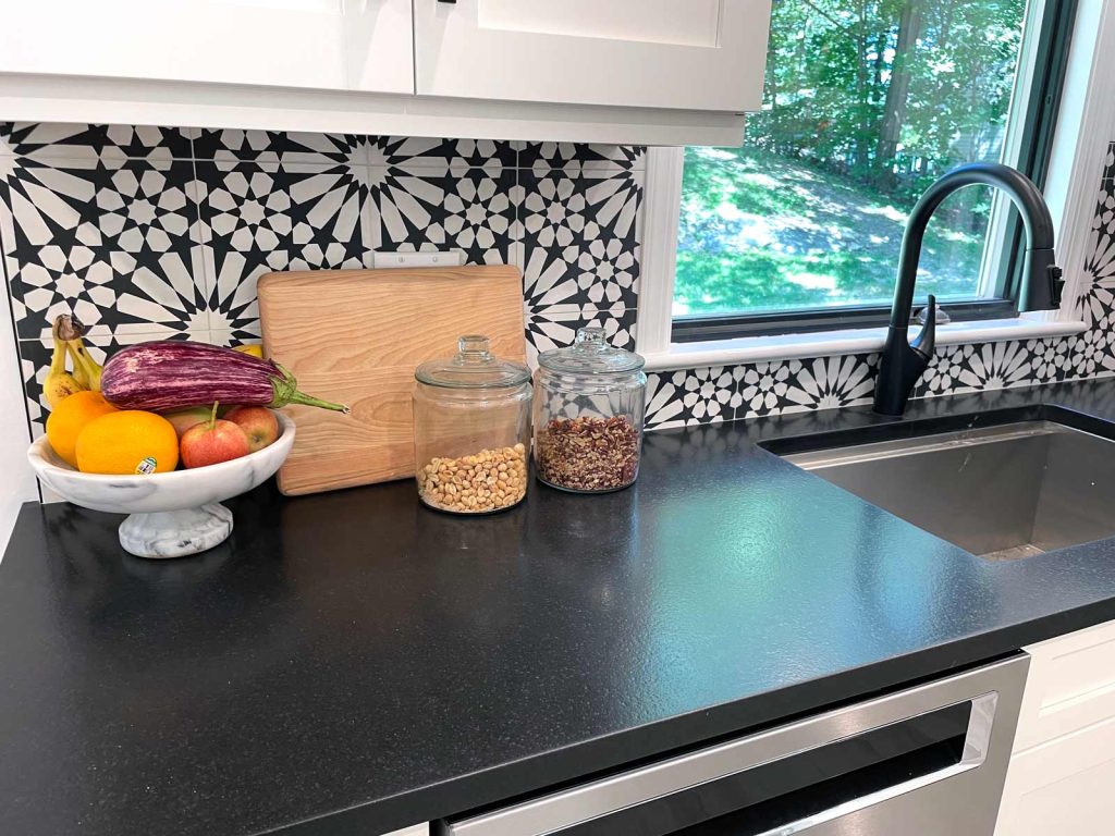 A kitchen remodel with ornate black and white backsplash by White Maple Construction