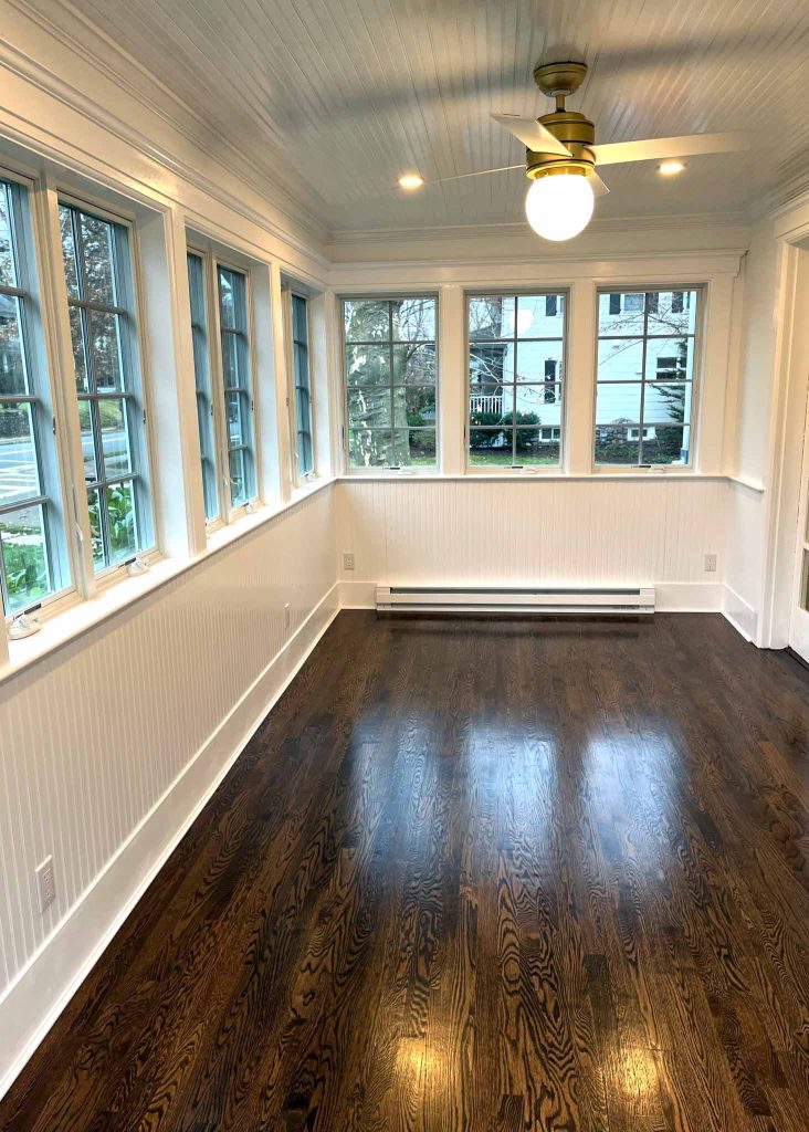 The interior of a sunroom addition with hardwood floors by White Maple Construction