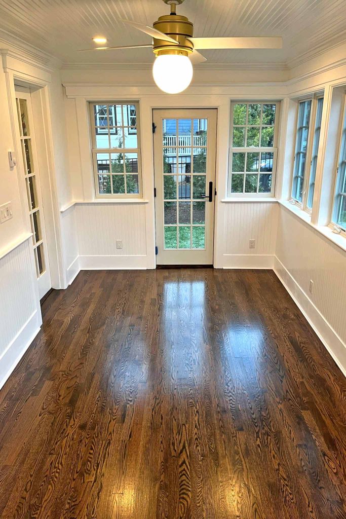 The interior of a sunroom addition in New Jersey with beautiful wood floors and white walls